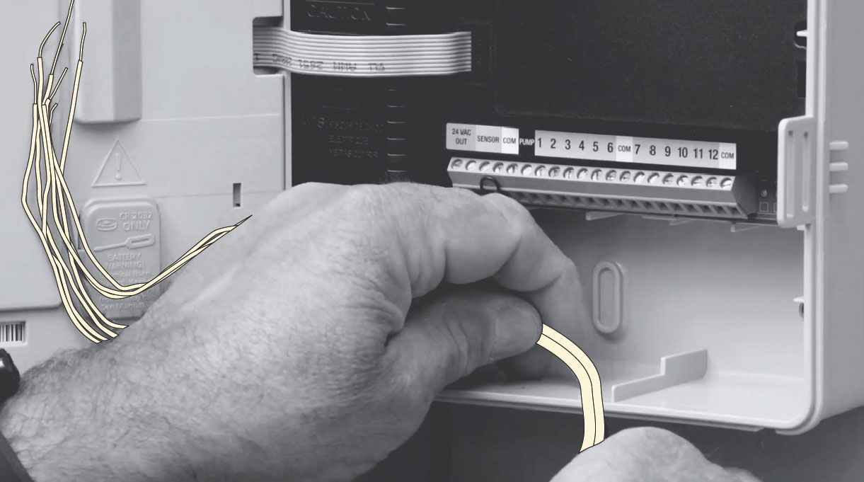 Persona manipulando los cables del programador de riego automático