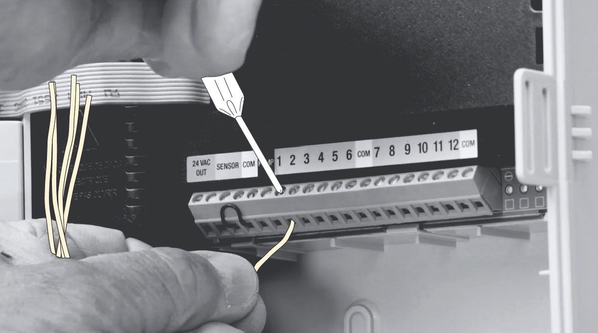 persona conectando los cables a las válvulas del programador de riego automático