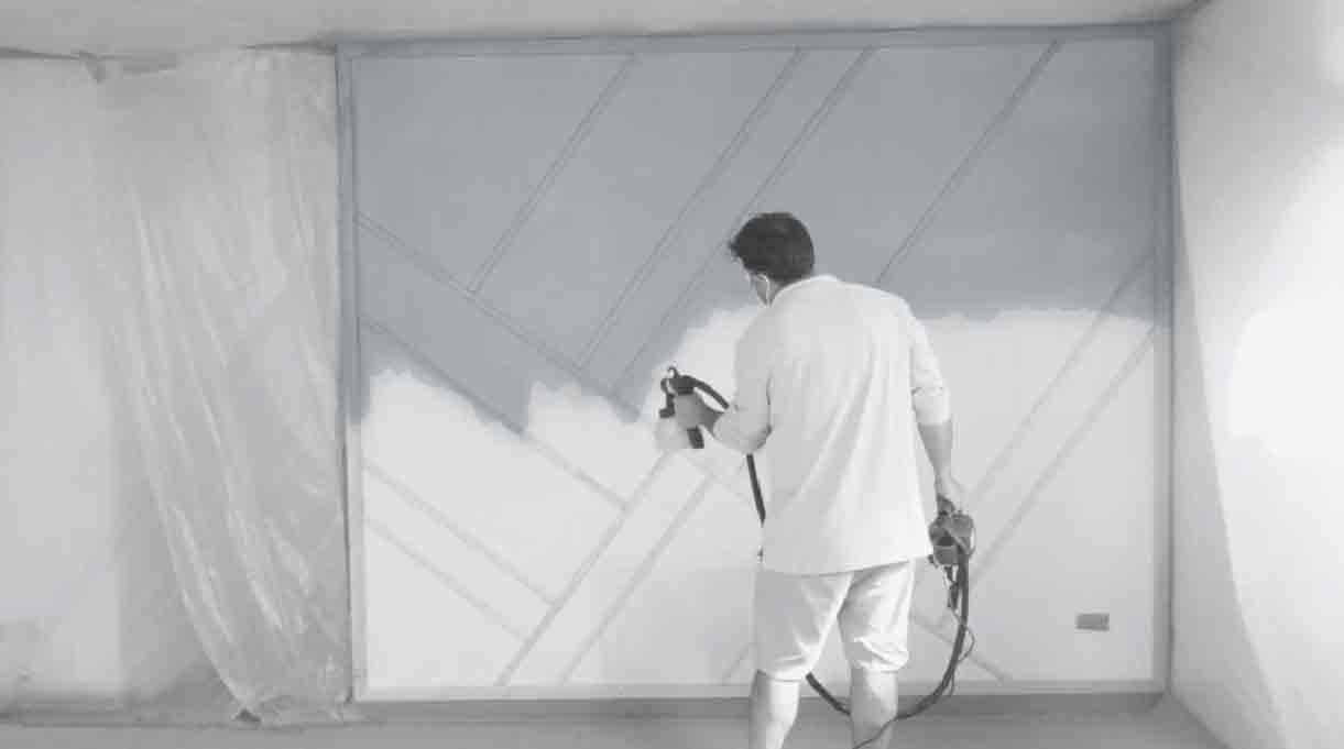 hombre pintando el muro con pistola pulverizadora