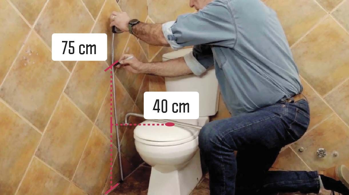 Alejandro Tardel midiendo para instalar las barras de seguridad a 75 cm desde el suelo y las barras para ayudar en el inodoro a 40 cm del eje del WC