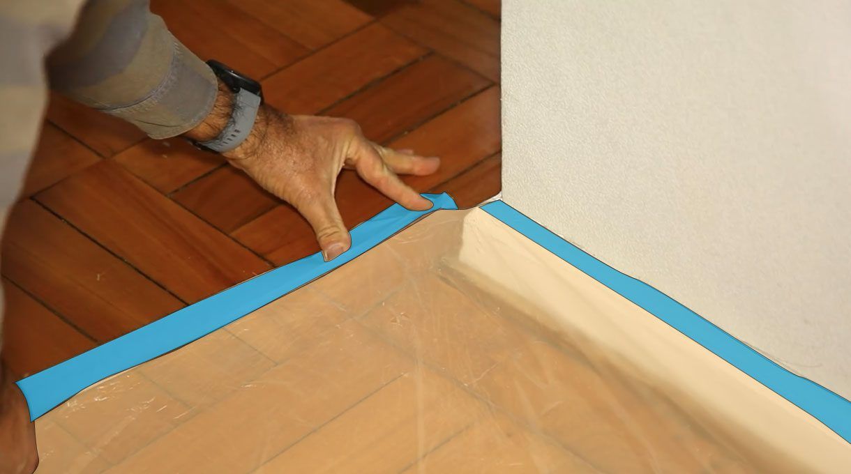 Tardel colocando cinta para enmascarar en el piso para que sujete un plástico protector para este