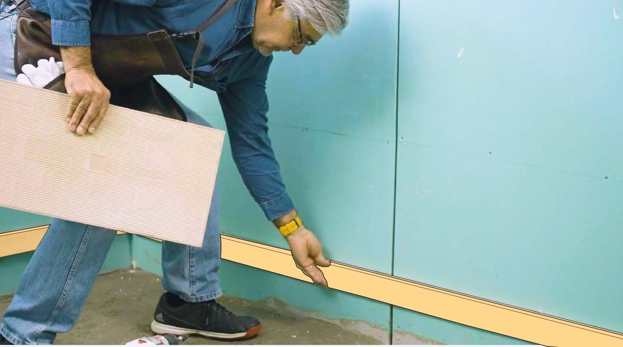 El conductor de Hágalo Usted Mismo, Alejandro Tardel, coloca una línea maestra con listones de madera en la base de una pared.