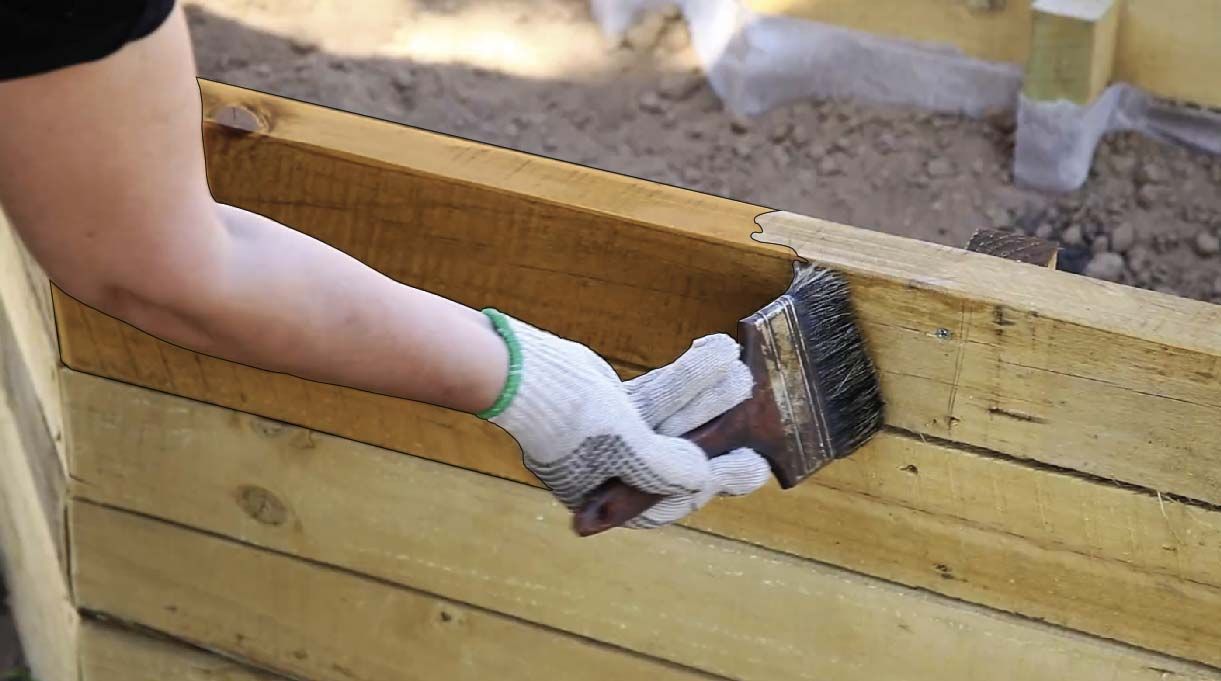 Brocha aplicando aceite impregnante a la madera para protegerla
