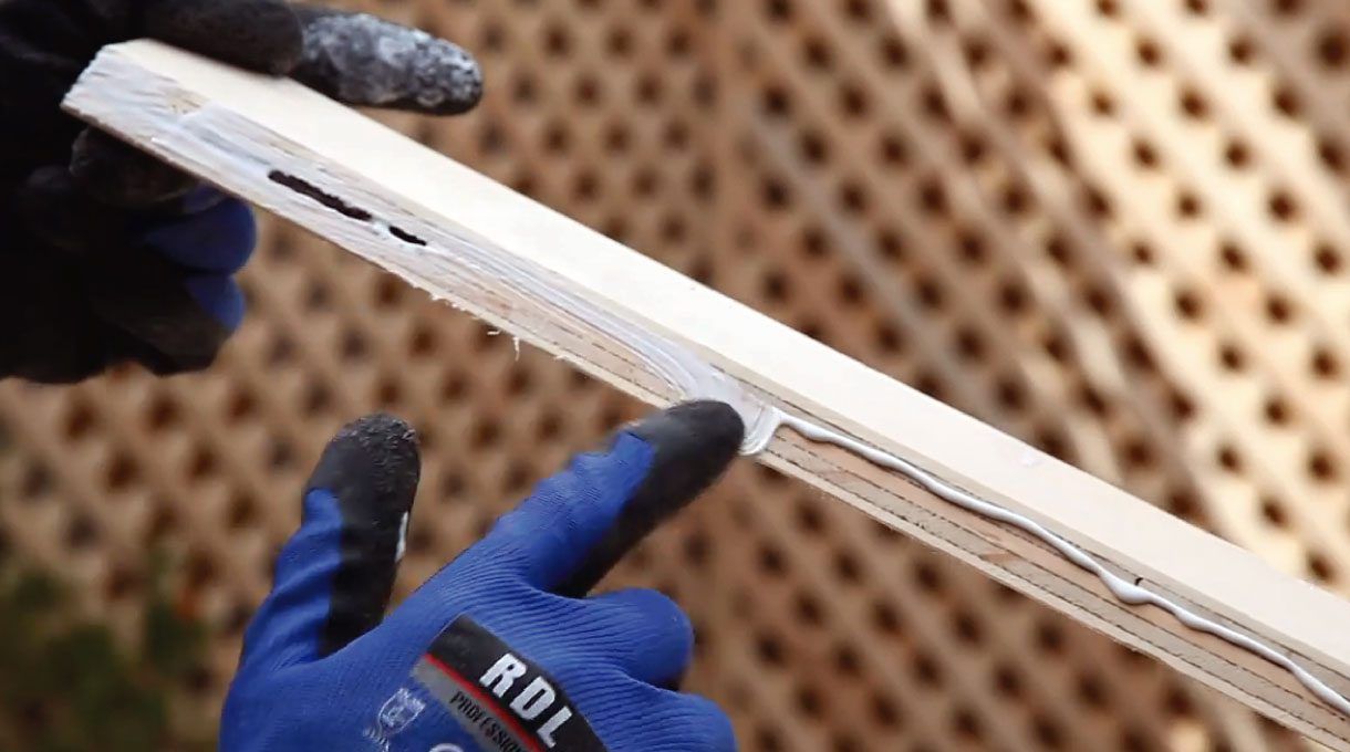 Guante azul aplicando cola fría en las uniones.