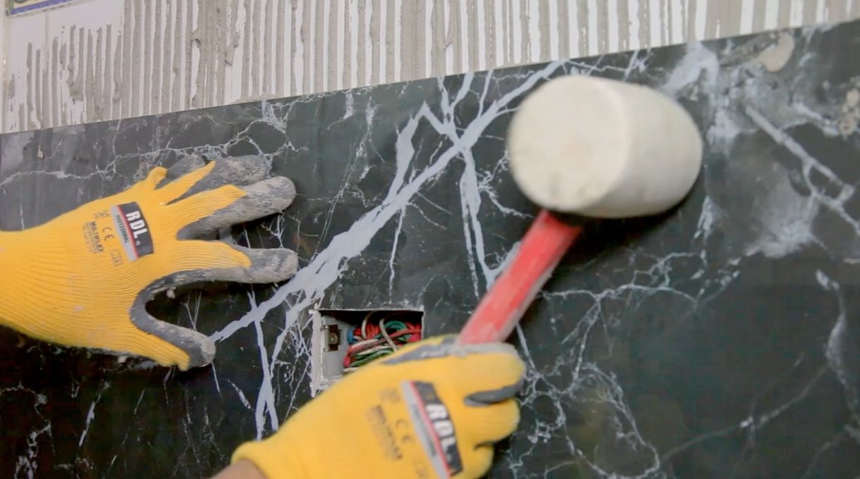 Golpeteo suave con combo de goma para asentar porcelanato en pared