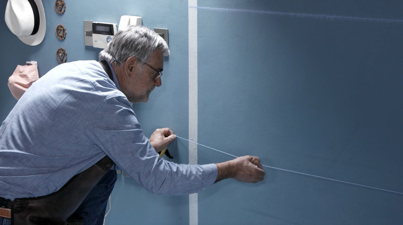 Una persona usa un tizador para marcar las líneas de la cuadrícula para el trazado del mural decorativo