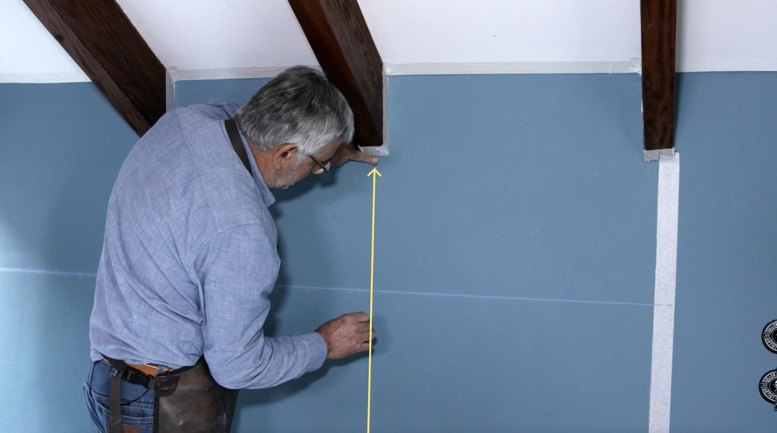 Una persona usa un tizador para marcar las líneas de la cuadrícula para el trazado del mural decorativo
