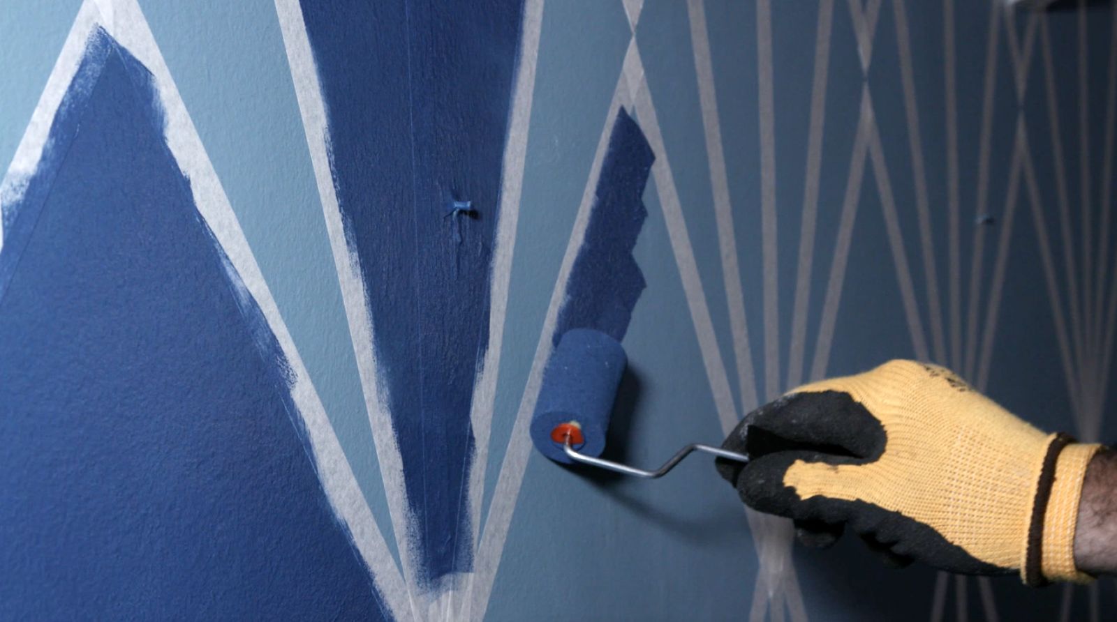 Una persona pinta parte del mural con esmalte al agua Kölor y un rodillo de esponja