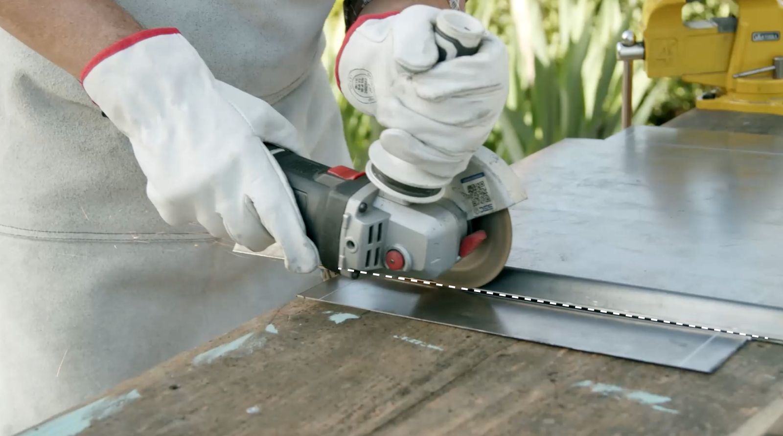 Persona realizando cortes superficiales en la plancha metálica con un esmeril angular