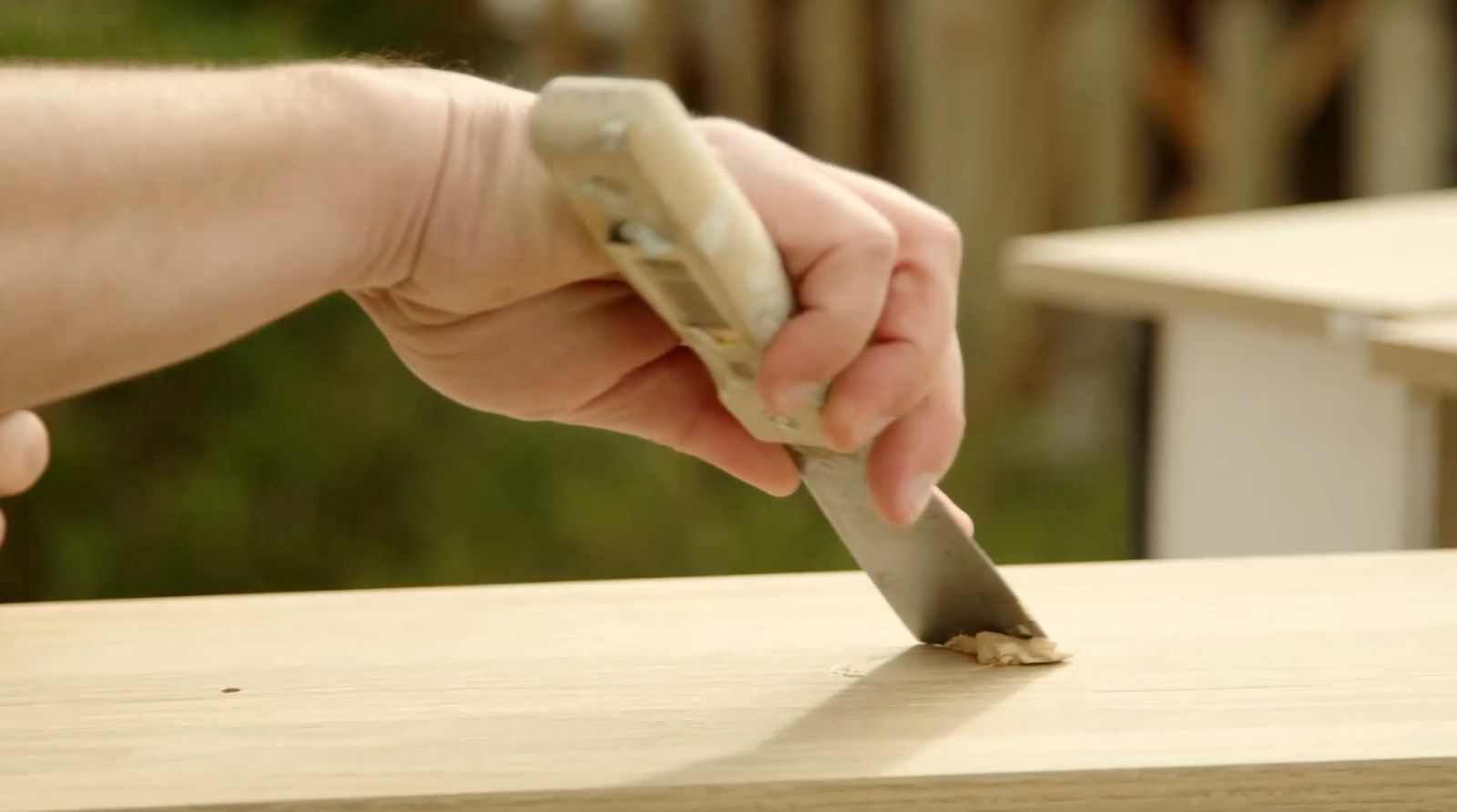 Se una mano con una espátula tapando imperfecciones con pasta de retape