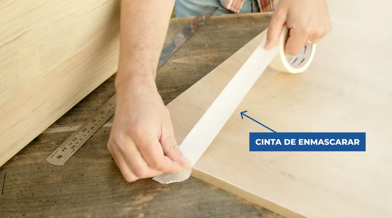 Persona poniendo una tira de cinta de enmascarar en la plancha de melamina