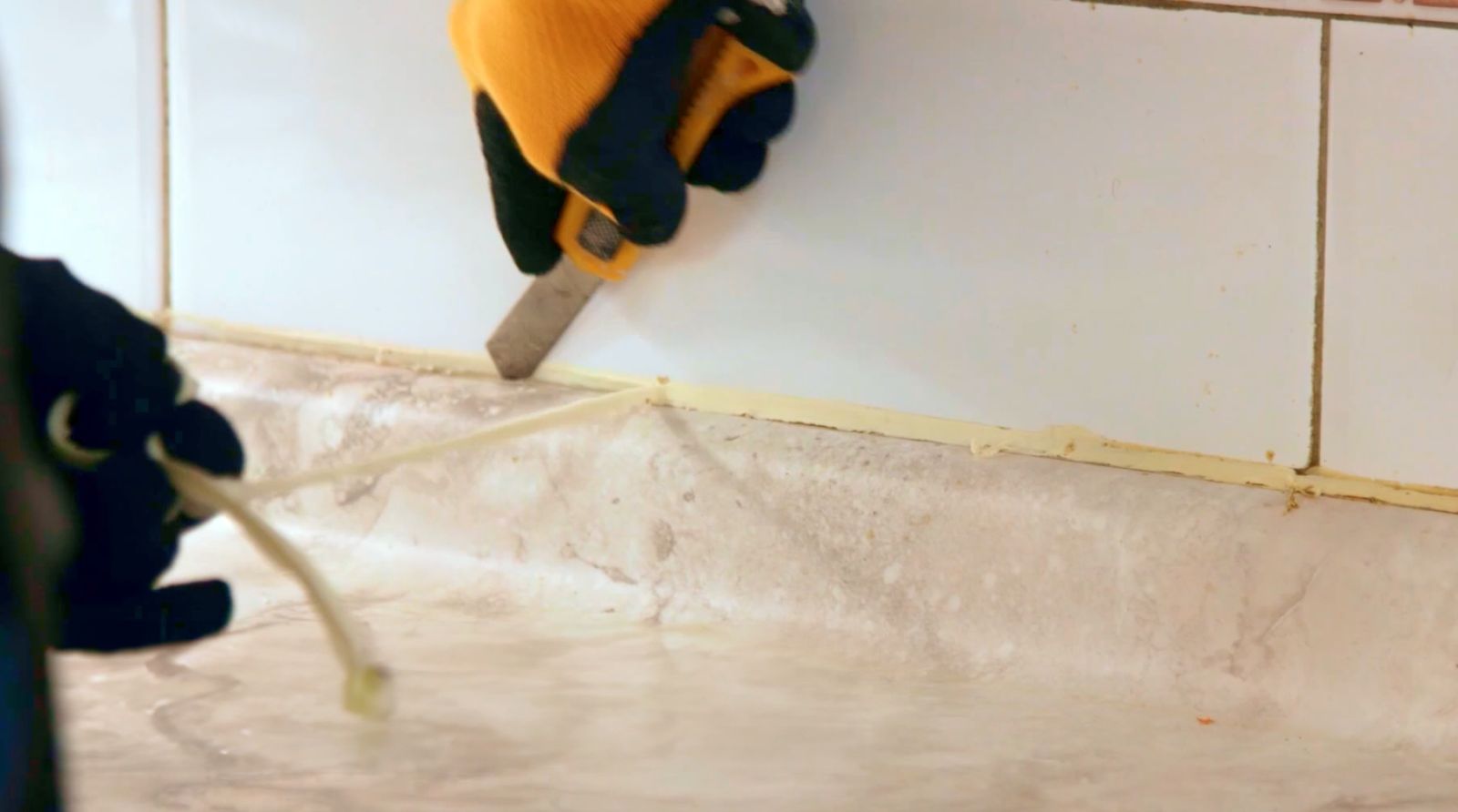 Una persona cortando la silicona que une el mesón al muro con cuchillo cartonero
