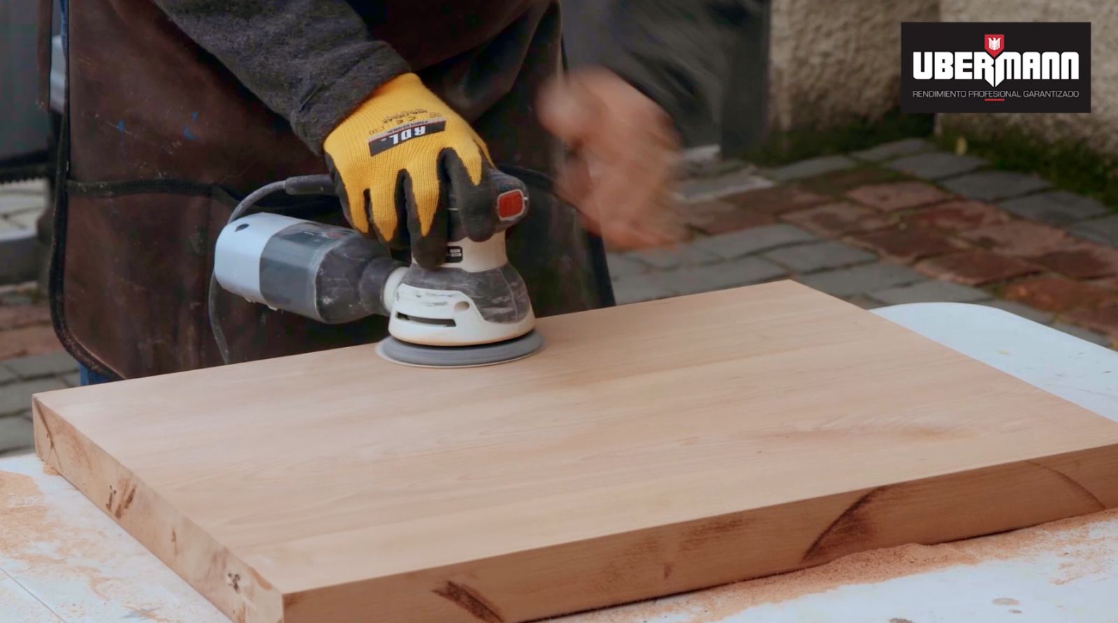 Una persona lijando la tabla de madera con lijadora orbital