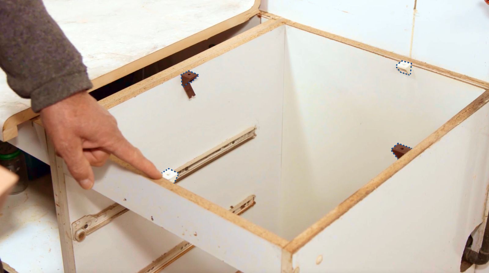 Una persona apunta a las 4 escuadras del mueble a las que irá fijada la tabla de madera