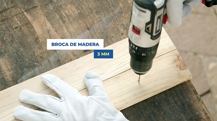 Una persona perfora superficialmente las tablas de pino con broca para madera de 3 mm