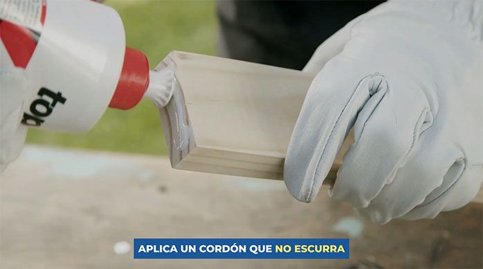 Una persona aplica cola fría en un canto del pino seco cepillado