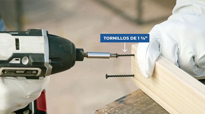Una persona fija el pino de Navidad con tornillos de 1 5/8