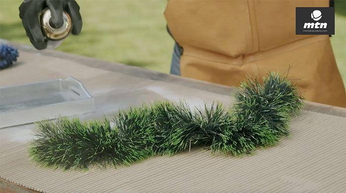 Una persona aplica pintura en spray a una guirnalda verde de Navidad