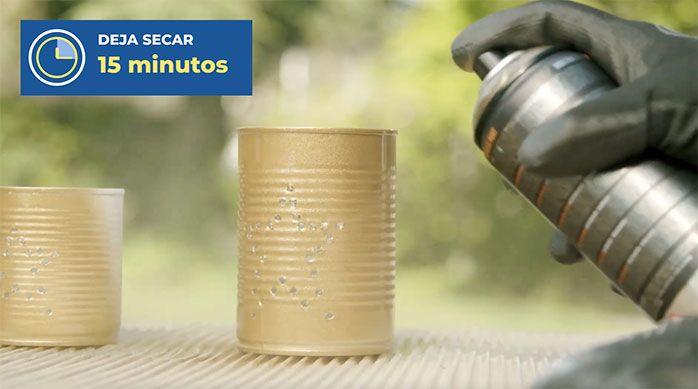 Una persona aplica spray dorado en las latas de conserva