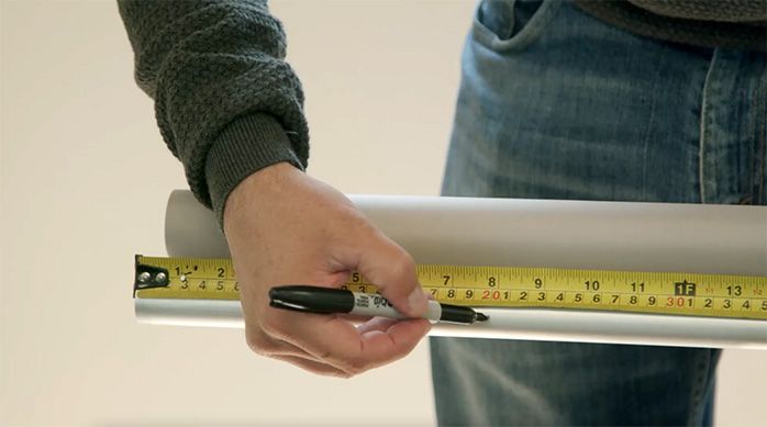 Una persona marca la cortina enrollable o roller para cortarla