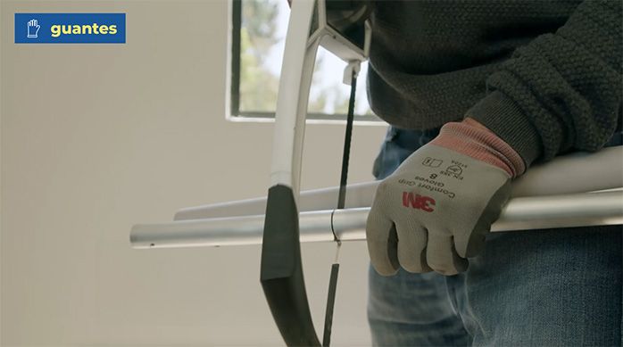 Una persona corta con una sierra el tubo de aluminio de la cortina enrollable o roller
