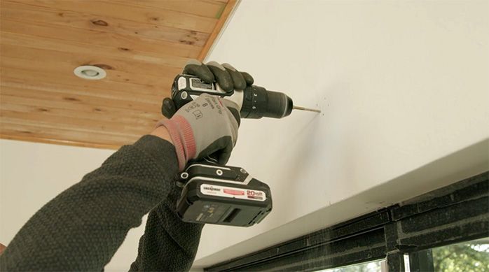 Una persona perfora el muro para instalar una persiana de pvc
