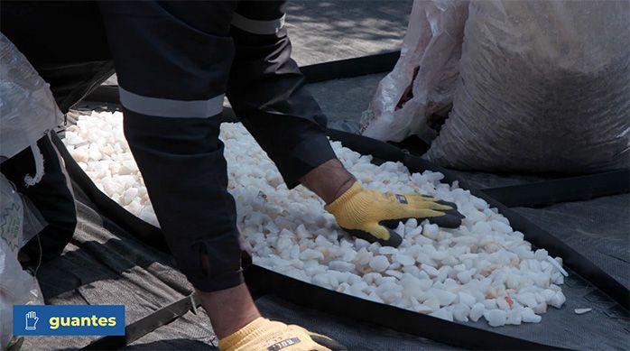 Una persona distribuye cuarzo blanco en uno de los pétalos del jardín de piedras