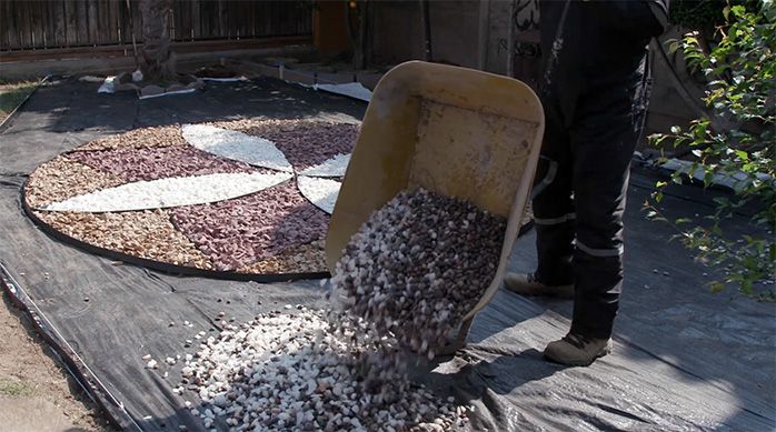 Una persona da vuelta una carretilla con piedras en el jardín de piedras