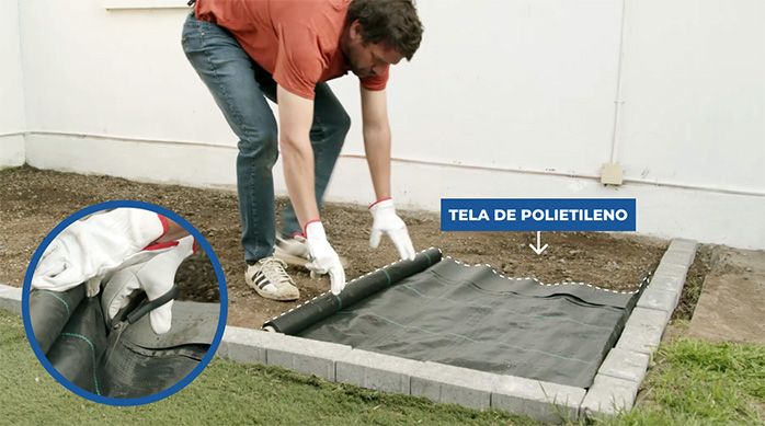 Una persona desenrolla una tela de polietileno en el piso de tierra