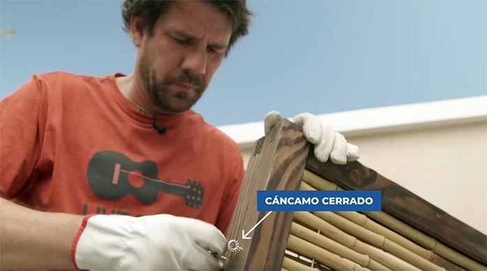 Una persona pone un cáncamo cerrado n°5 en el panel de bambú