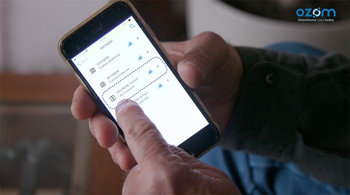 Una persona indica con su dedo el celular en donde está configurando el sensor de puerta hyundai