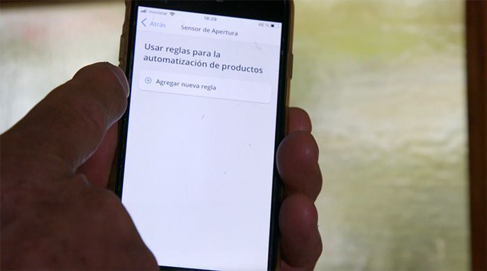 Una persona indica en el celular la configuración de las reglas para el uso del sensor de puerta
