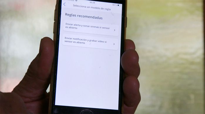 Una persona muestra en el celular las reglas recomendadas para el sensor de puerta