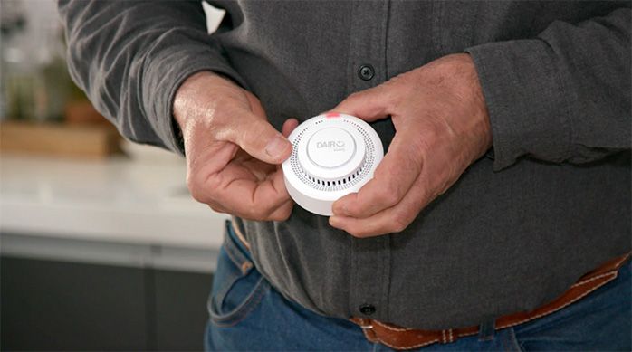 Una persona muestra el detector de humo con su luz encendida