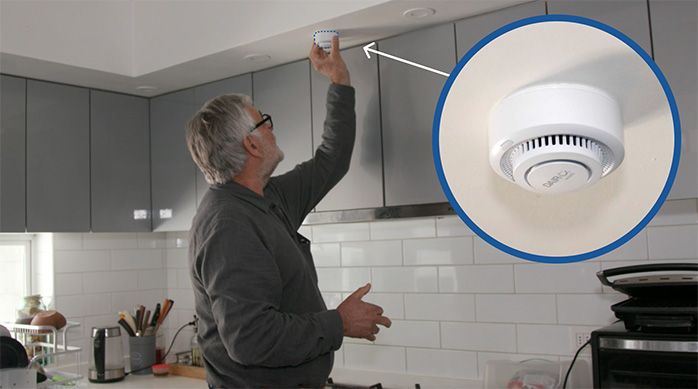 Una persona pega el detector de humo en el cielo de la cocina