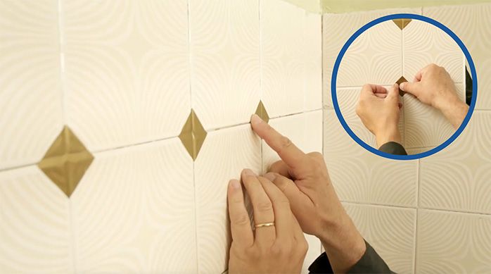 Una persona pega los adhesivos para cerámicos en los muros del baño