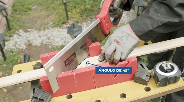Una persona corta una moldura de madera con una caja de ingletes y serrucho costilla