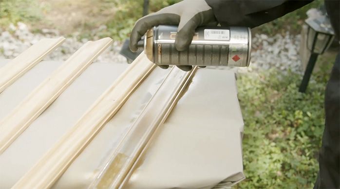 Una persona pinta las molduras de madera con pintura en spray dorada