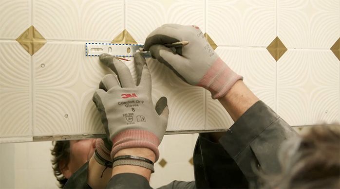 Una persona marca el lugar de instalación del apliqué en el muro de cerámica