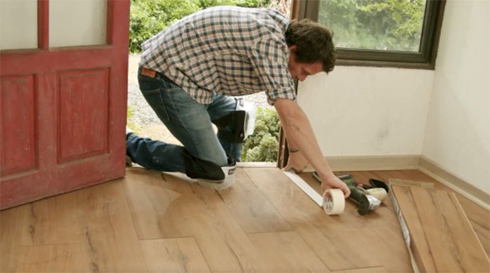 Una persona marca con cinta de enmascarar la zona a reemplazar del piso laminado dañado por humedad