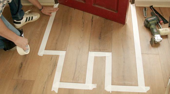 Se ve la zona delimitada del piso laminado con cinta de enmascarar