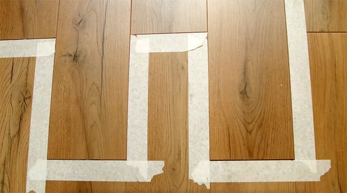 Se ve el piso laminado reparado, pero aún con la cinta de enmascarar