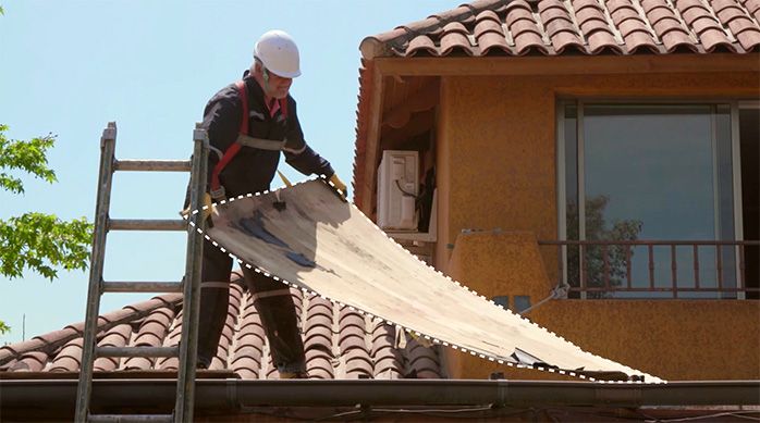 Una persona levanta una plancha del techo con filtración de agua