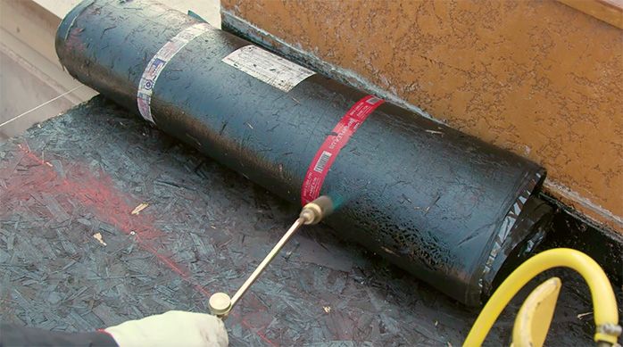 Una persona calienta la membrana asfáltica