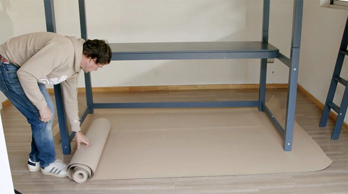Una persona desenrolla un rollo de cartón en el piso de la habitación