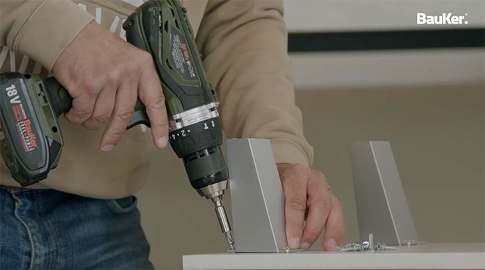 Una persona atornilla las patas al mueble