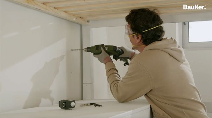 Una persona perfora el muro para colocar un soporte para monitor