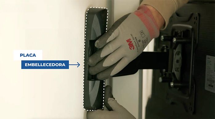 Una persona instala la placa embellecedora para tapar la fijación del soporte de monitor