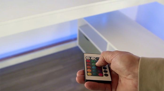 Una persona usa el control remoto de las luces led para cambiar su color a azul