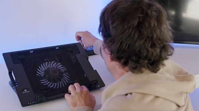Una persona instala un ventilador para notebook en el camarote gamer